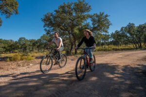 a couple riding mountain bikes on a ranch trail